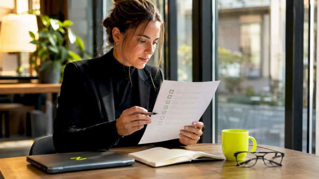 Une femme passe en revue sa liste de tâches SEO installée à son bureau chez elle.