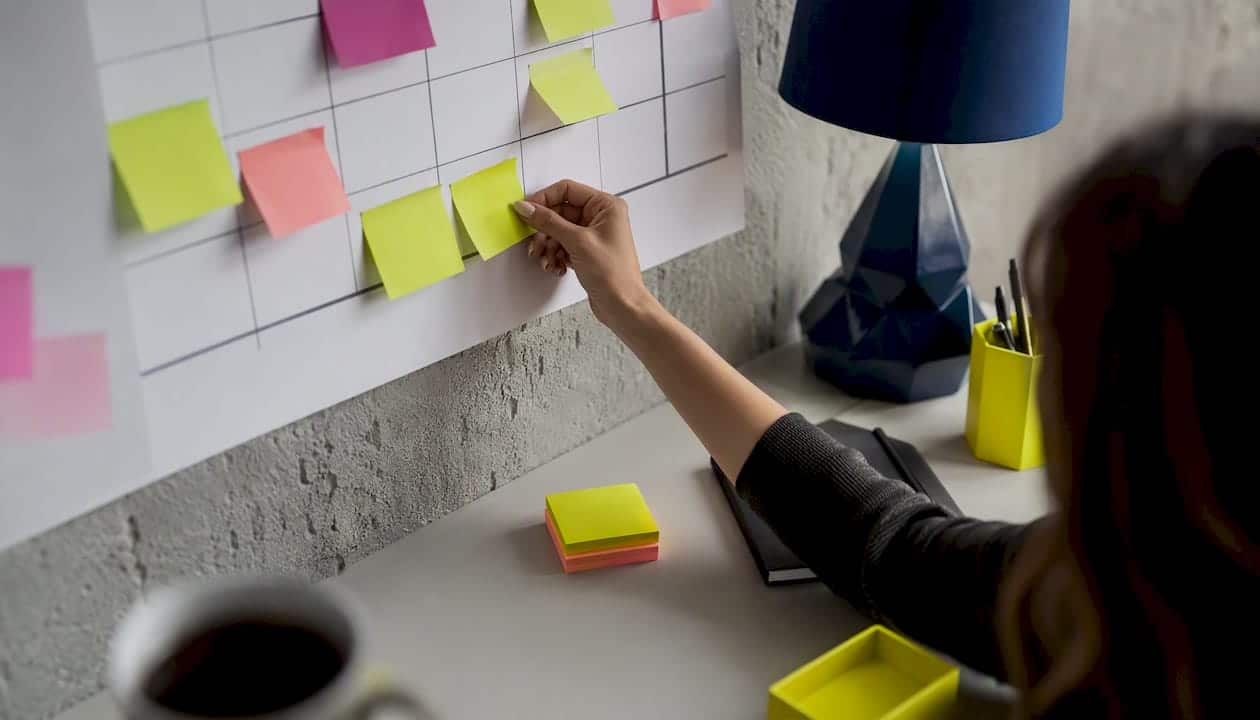 Je planifie mon calendrier éditorial à la main, en utilisant des post-it pour visualiser et organiser mes idées.