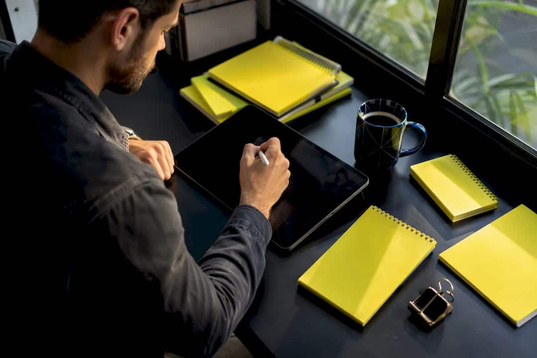 Des mains dessinent l’ébauche d’une boutique en ligne sur une tablette.