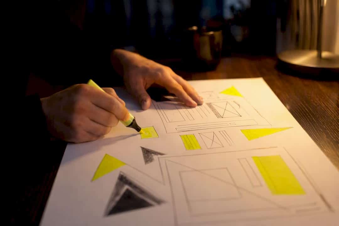 Des mains qui annotent une maquette de page d'atterrissage sur une table