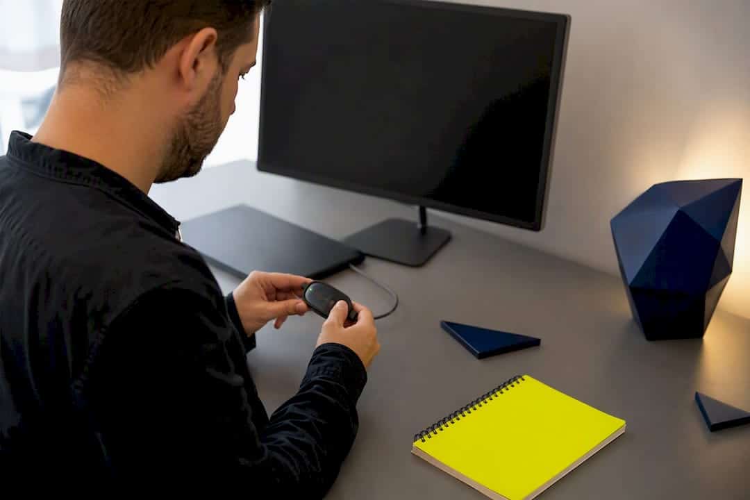 Mains utilisant une souris près d'un ordinateur portable sombre sur un bureau de marque